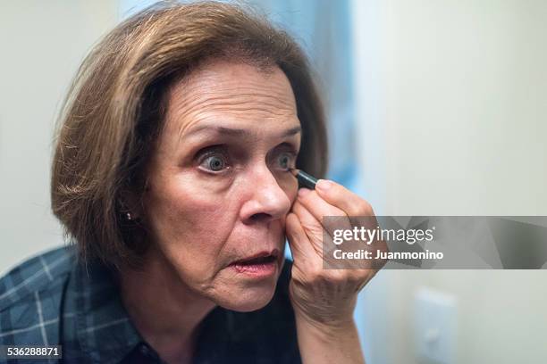 senior women painting her eyes - 70s eye makeup stockfoto's en -beelden