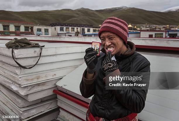 Tibetan nomad checks a fake gold cap that he had put on a tooth by a street dentist during a break from harvesting cordycep fungus on the 15th day of...