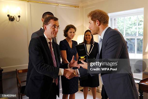 Prince Harry presents U.S. Staff Sergeant Elizabeth Marks' gold medal to Consultant Intensivist Dr Alain Vuylsteke and the other members of the...