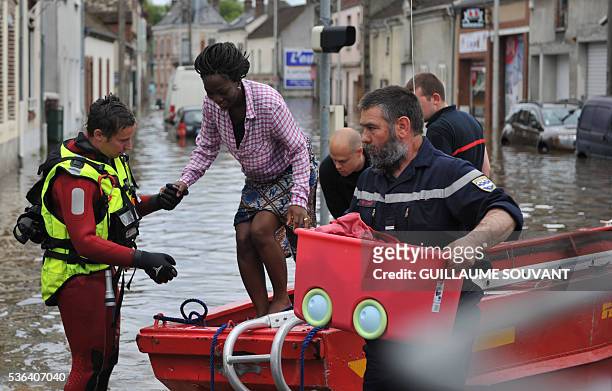 Firefighters help a woman to disembark a boat as the city is flooded due to heavy rainfalls at Montargis, central France, on June 01, 2016....