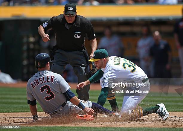 Ian Kinsler of the Detroit Tigers is tagged out at home plate by Oakland Athletics pitcher Jesse Hahn after trying to score from second base on a...