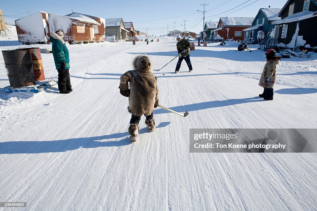 Inuit children playing ice hockey