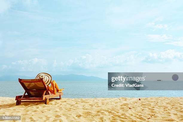 frau sonnenbaden im strand-stuhl - strand liegen stock-fotos und bilder