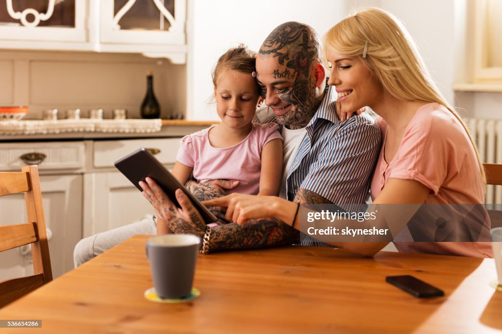 Smiling parents surfing the Internet with daughter on touchpad.