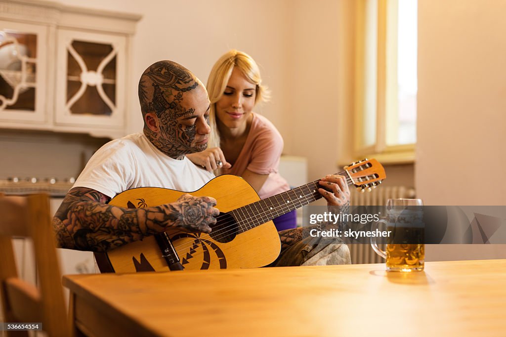 Young man playing acoustic guitar to his girlfriend at home.
