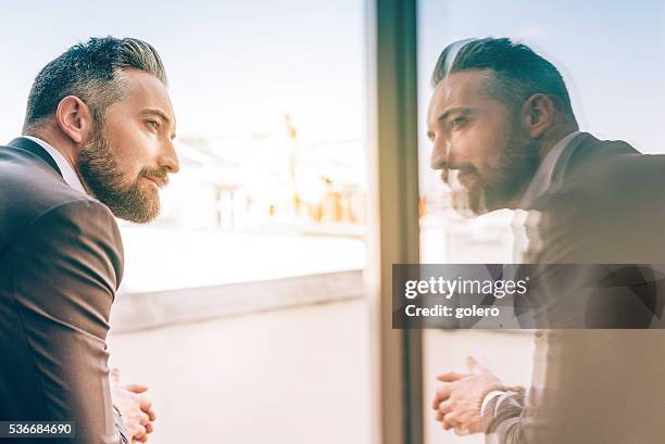 bearded business man reflecting himself in window glass - economy business and finance stock pictures, royalty-free photos & images