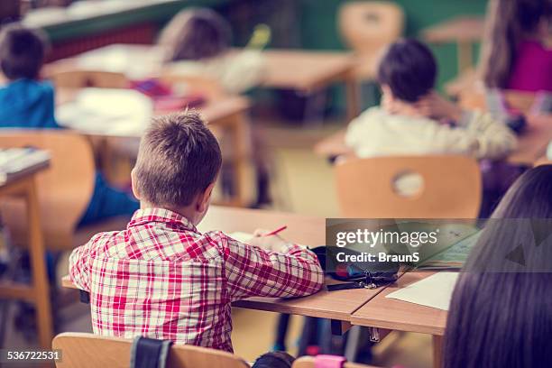kleiner junge im klassenzimmer. - kind im grundschulalter stock-fotos und bilder