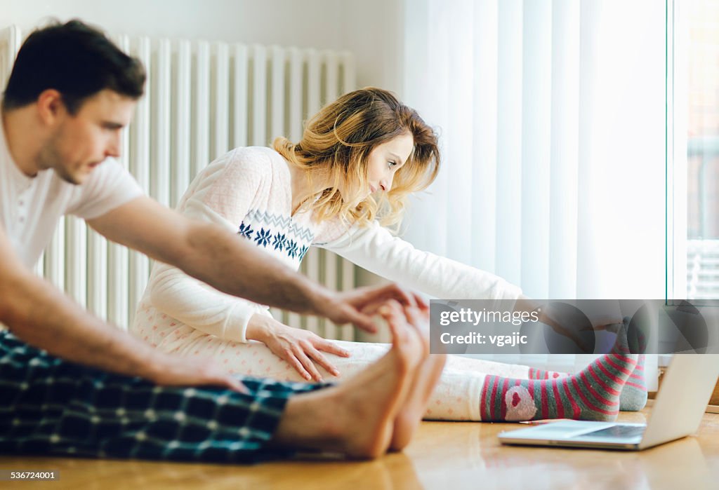 Couple Exercise in a living room with laptop.