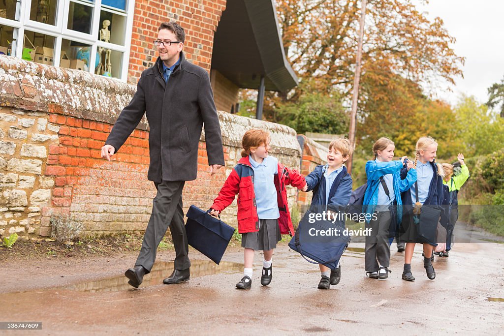 Children Walking Out of School With Their Teacher