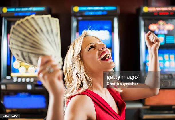 woman in casino winning at slot machine. - casino winner stock pictures, royalty-free photos & images