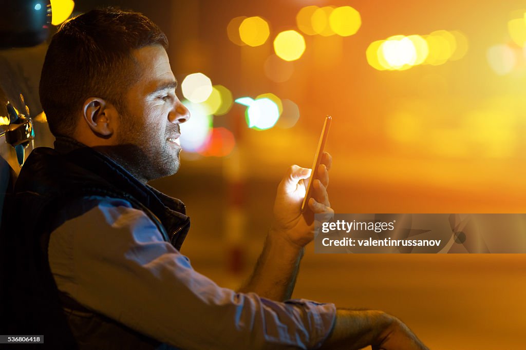 Young man sitting next to his cat at night