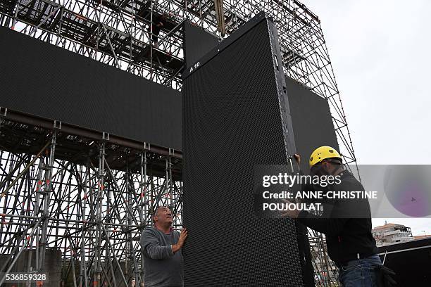 Workers install giant screens in the fanzone site for the UEFA Euro 2016 on the Prado beaches in Marseille where supporters will gather to watch the...