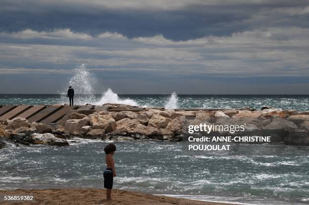 People stands by the sea next to the fanzone site for the UEFA Euro 2016 on the Prado beaches in Marseille where supporters will gather to watch the...