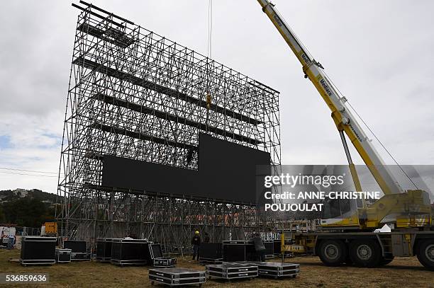 Workers install giant screens in the fanzone site for the UEFA Euro 2016 on the Prado beaches in Marseille where supporters will gather to watch the...