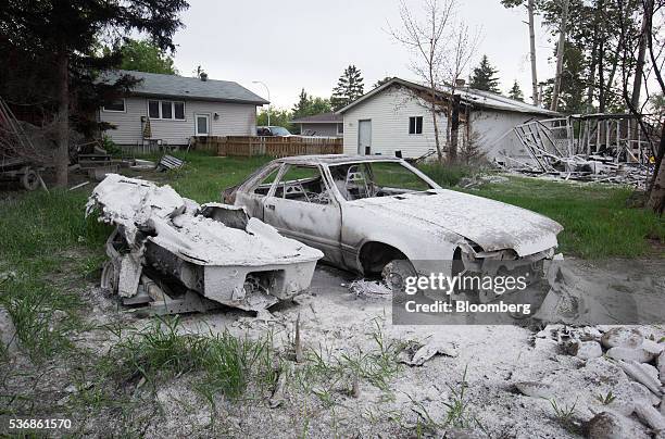 Boat and car destroyed by wildfire sit in the backyard of a house in Fort McMurray, Alberta, Canada, on Wednesday, June 1, 2016. Residents began...