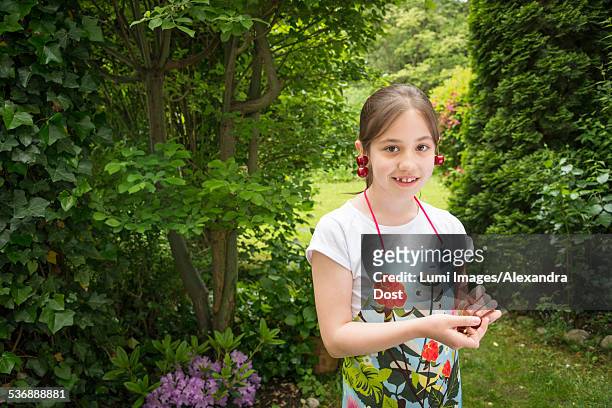 girl in garden, cherries dangling from her ears - alexandra dost stock-fotos und bilder