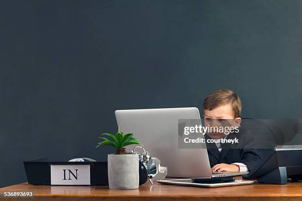 humorous image of young boy working on a laptop computer - spela vuxen bildbanksfoton och bilder