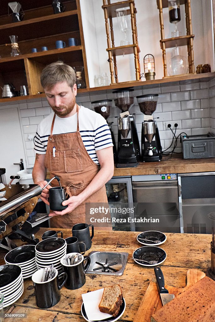 Barrista heats milk in cafe