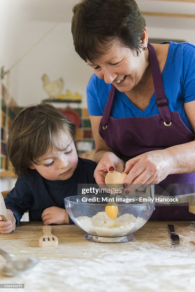 A woman and a child cooking at a kitchen table, making fairy cakes.