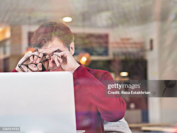 tired man working on laptop - bloodshot fotografías e imágenes de stock
