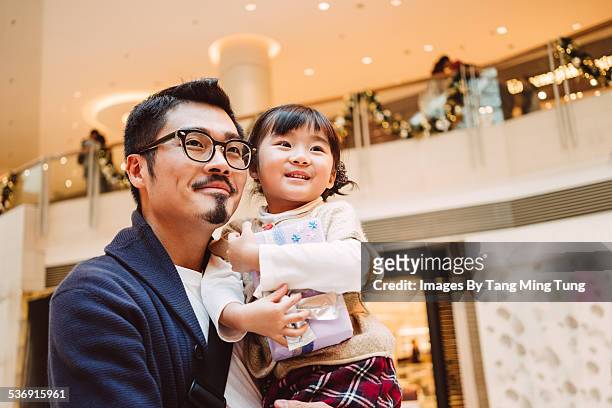 young dad holding daughter joyfully in mall - leanincollection father stock pictures, royalty-free photos & images