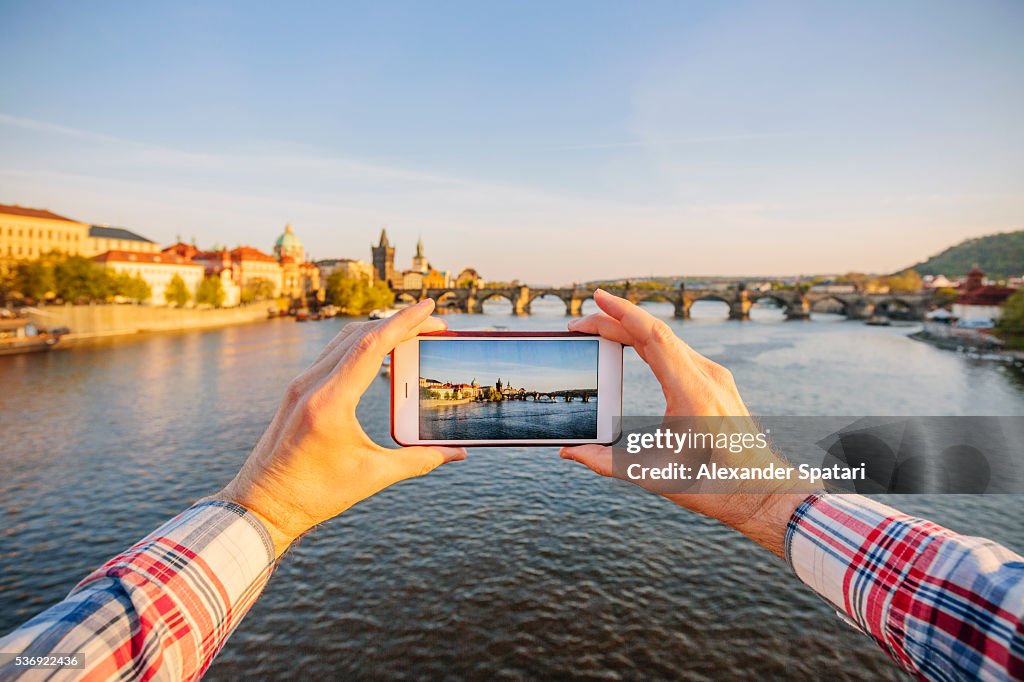 Tourist photographing Charles Bridge in Prague with smartphone