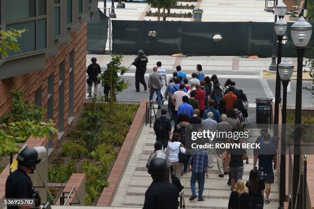 Security personnel escort people from the University of California Los Angeles campus after two people were confirmed dead following a shooting at...