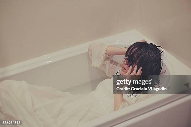 girl in bath with white dress - woman bath tub wet hair stock pictures, royalty-free photos & images
