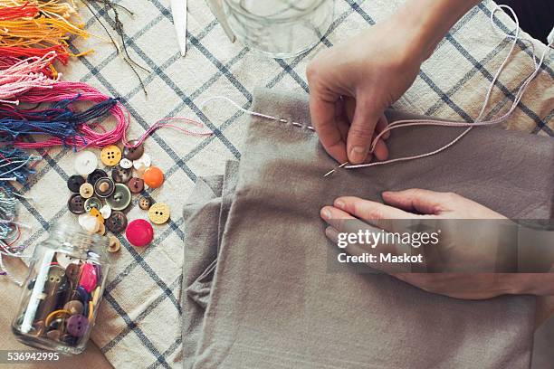 high angle view of woman stitching fabric on table at home - cucitura foto e immagini stock