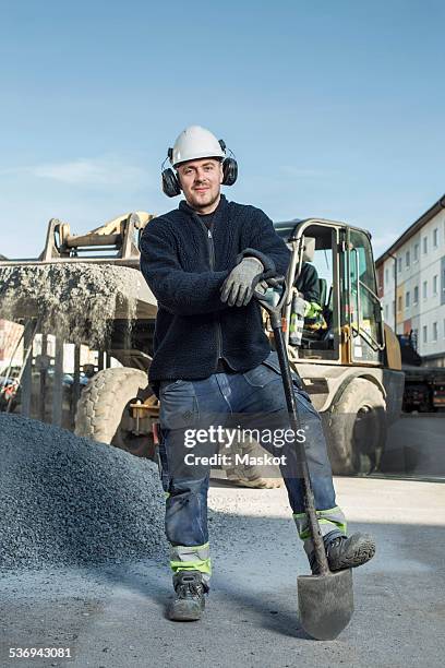 full length portrait of confident worker standing at construction site - laborer stock-fotos und bilder