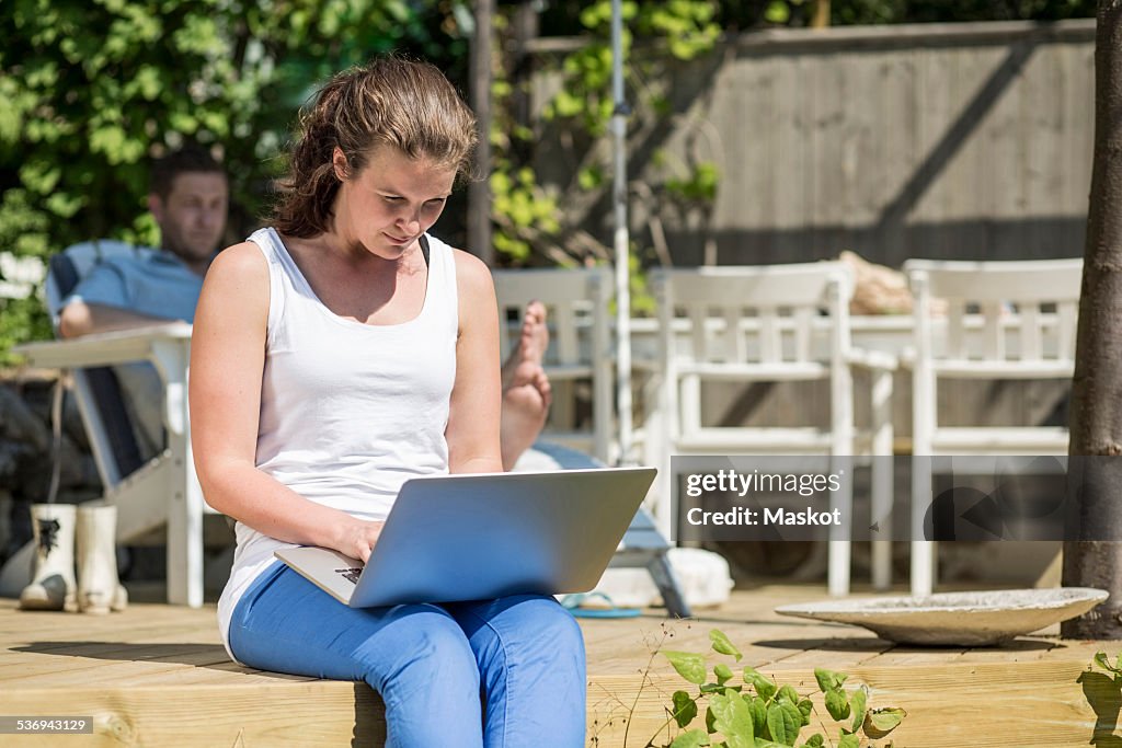 Mid adult woman using laptop on terrace