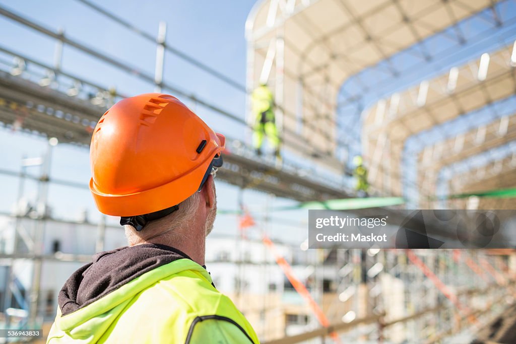 Rear view of worker looking at colleagues working at construction site