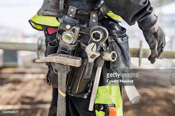 midsection of construction worker wearing tool belt at site - cintura per gli attrezzi foto e immagini stock