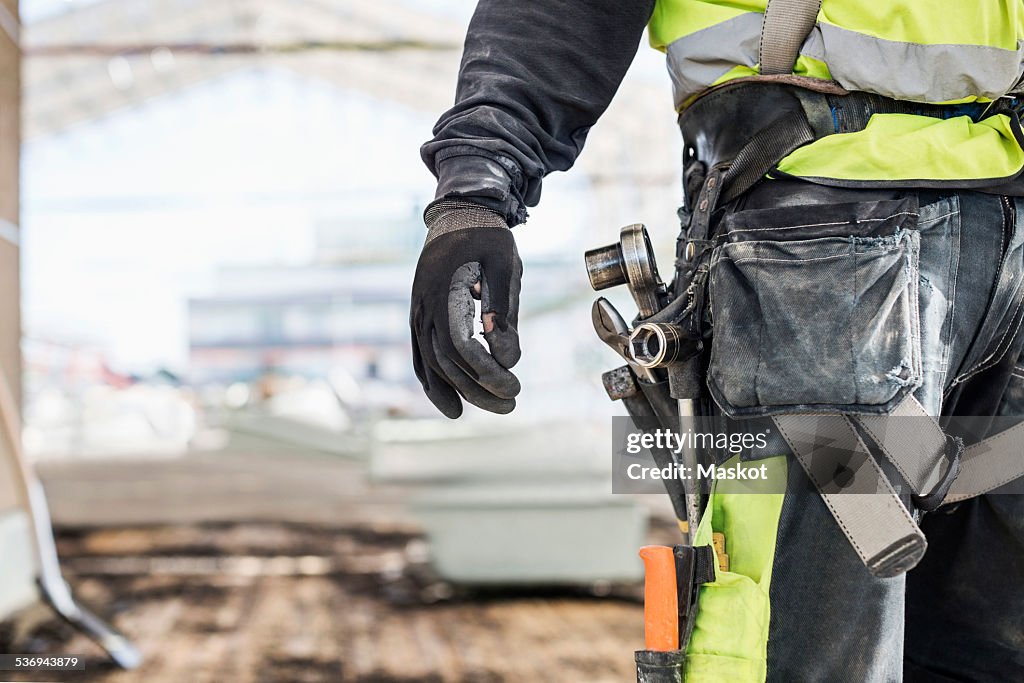 Midsection of worker wearing tool belt at construction site