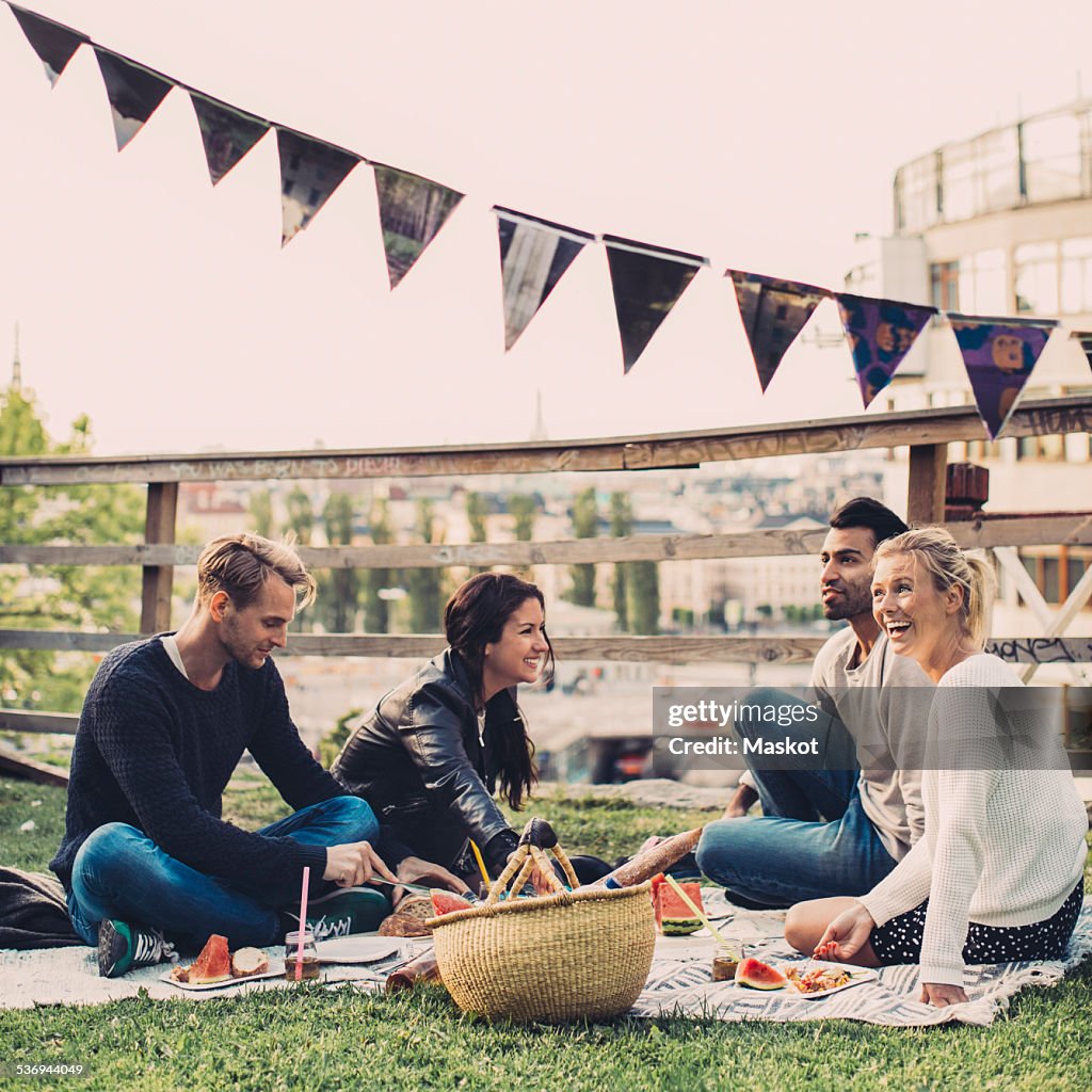Happy friends enjoying picnic on roof garden