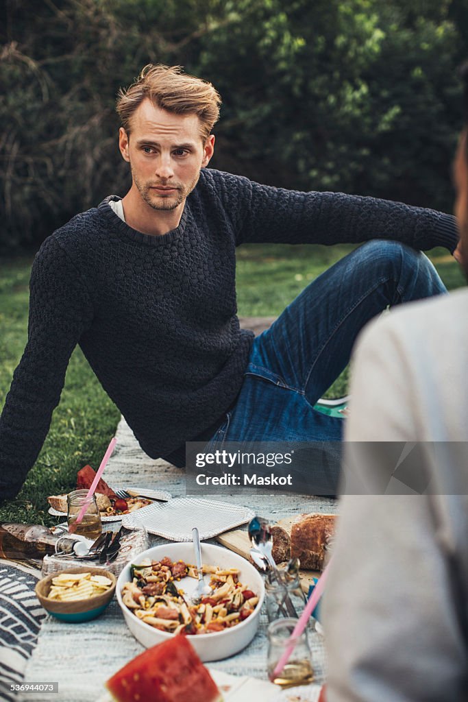 Thoughtful man sitting by breakfast at rooftop party