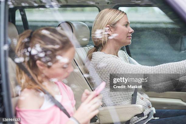 woman driving while daughter using mobile phone in car - daughter driving stock pictures, royalty-free photos & images