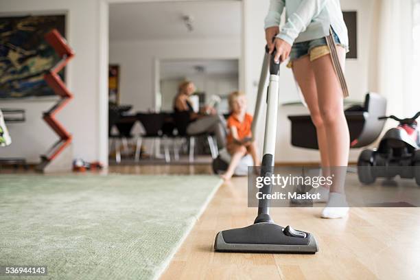 low section of girl cleaning floor with vacuum cleaner at home - vacuum cleaner woman stockfoto's en -beelden