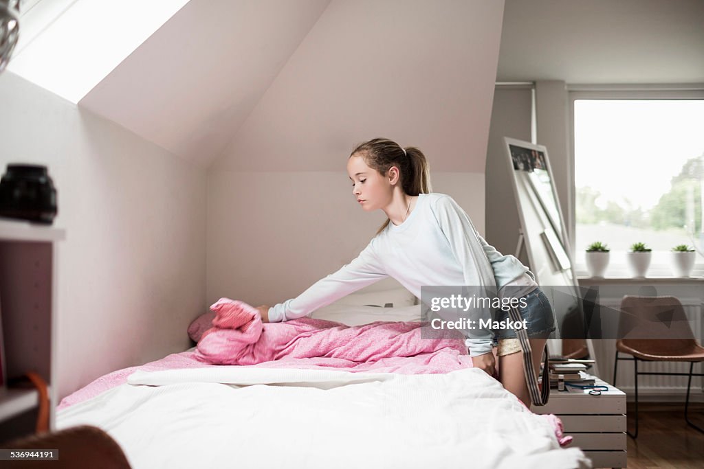 Girl making bed at home