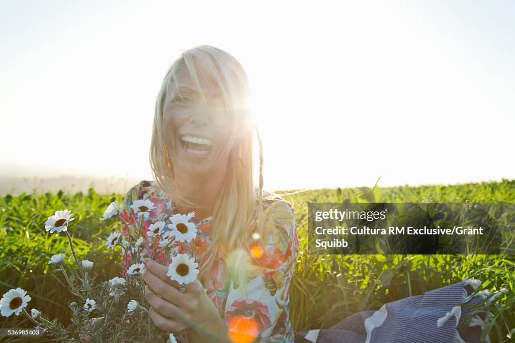 Young woman picking daisies whilst laughing