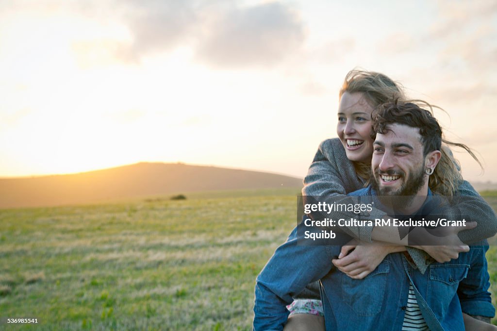 Happy young couple in rural field, Dorset, England