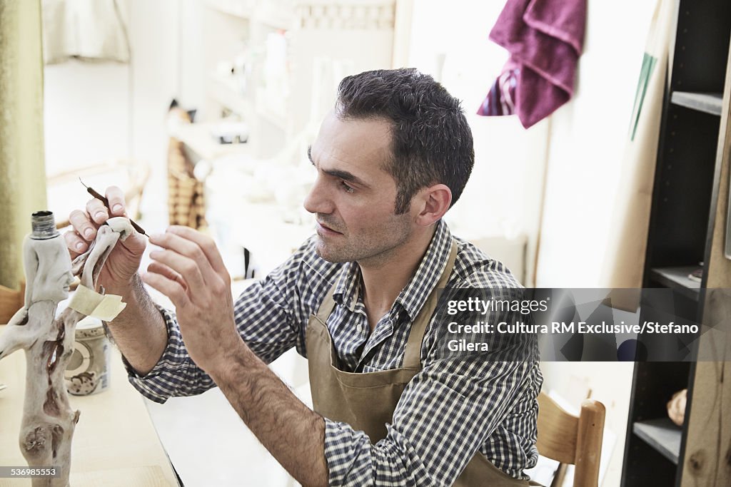 Mid adult male sculptor constructing table lamp in studio