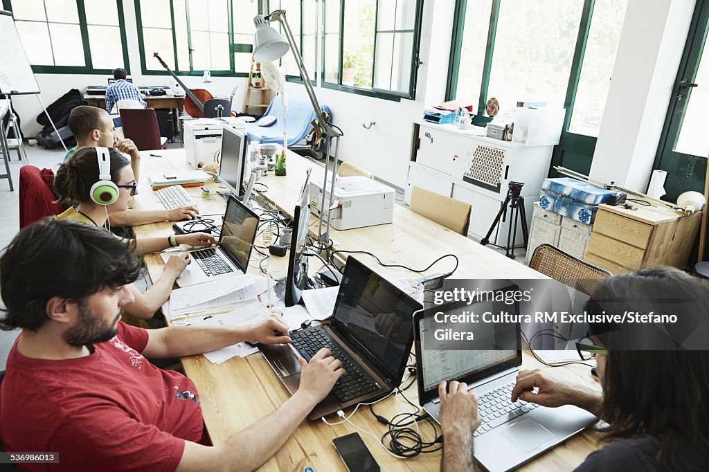 High angle view of male and female office workers typing on laptops in office