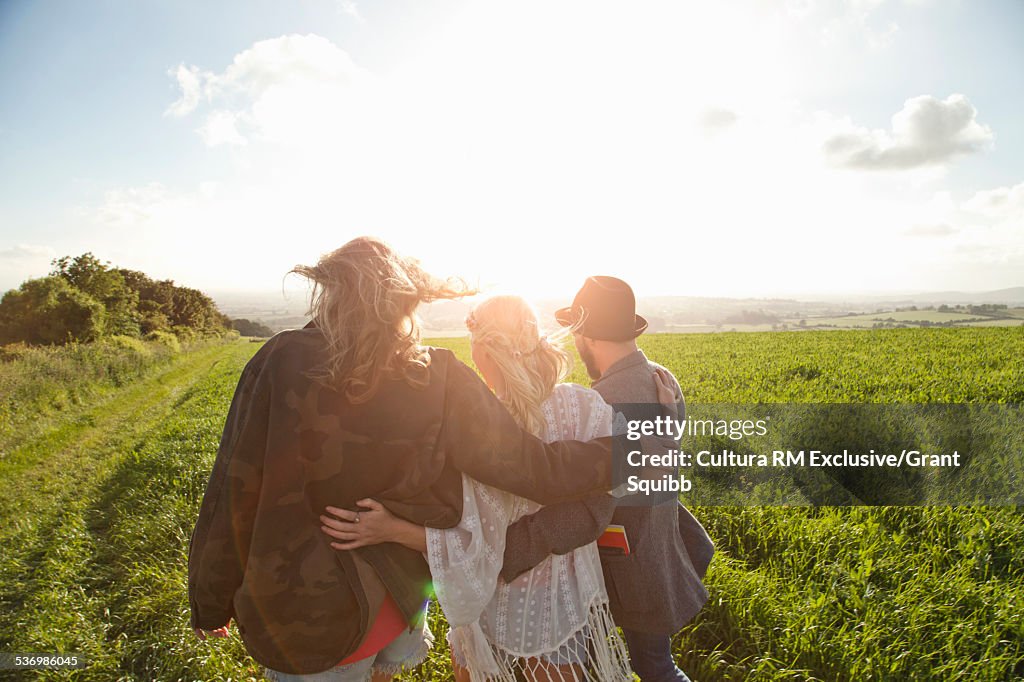 Rear view of three young adult friends in grassy field, Dorset England