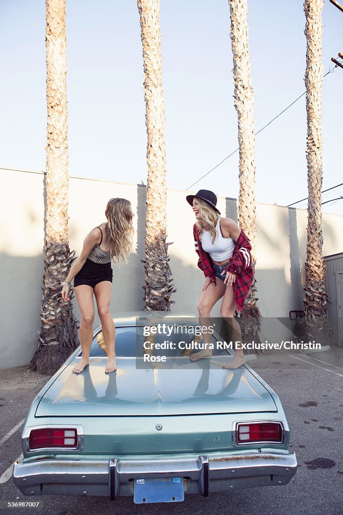 Two female friends dancing on car boot