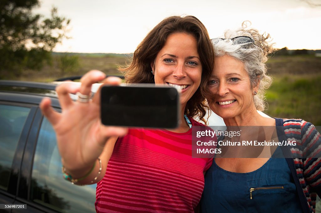 Mother and daughter taking selfie by car, Studland, Dorset