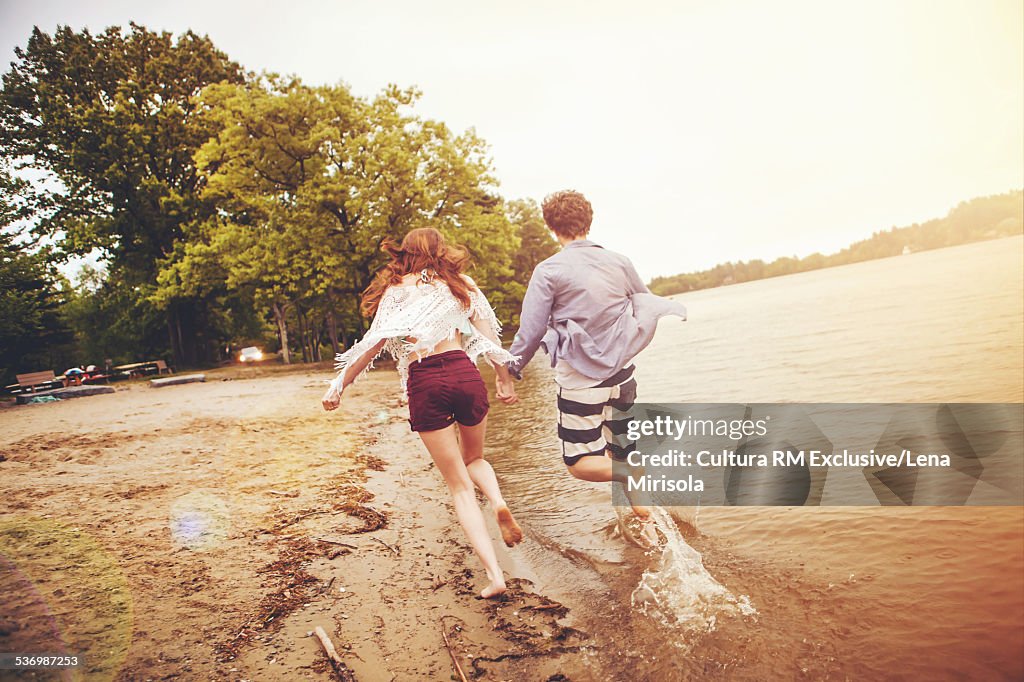 Young couple running on beach holding hands