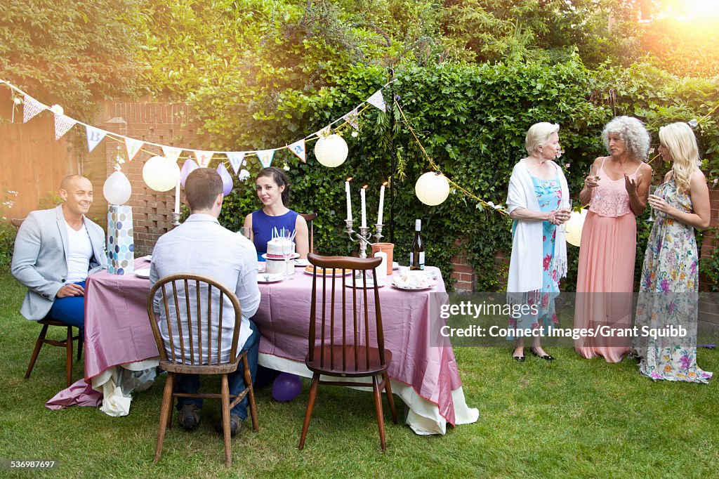 Family and friends chatting around table at garden party