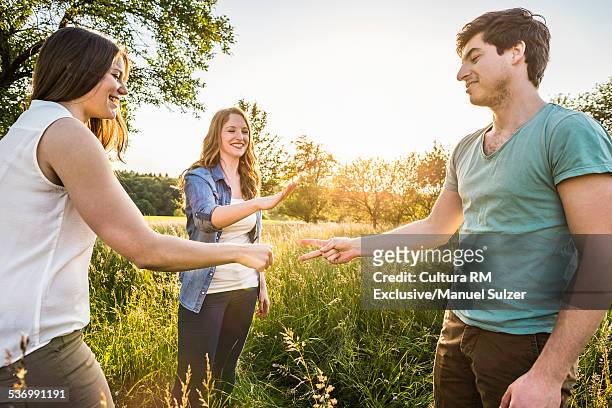 group of friends in field playing scissors, paper, stone - rock paper scissors stock pictures, royalty-free photos & images
