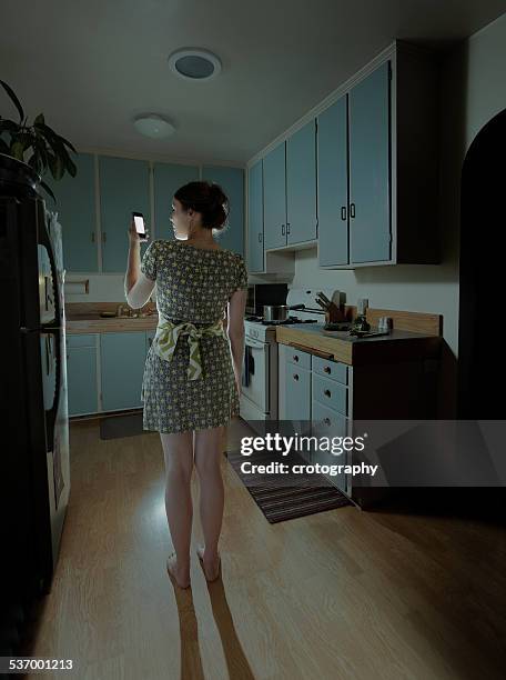 woman with smartphone in kitchen at night - femme de dos smartphone photos et images de collection